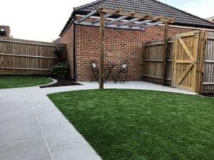 artificial lawn in back garden with pergola and limestone paving