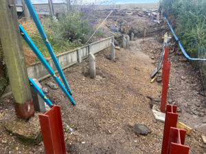 steep bank with red coloured steels inserted to support decking