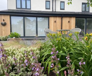 view of new living room extension across mature herbaceous planting