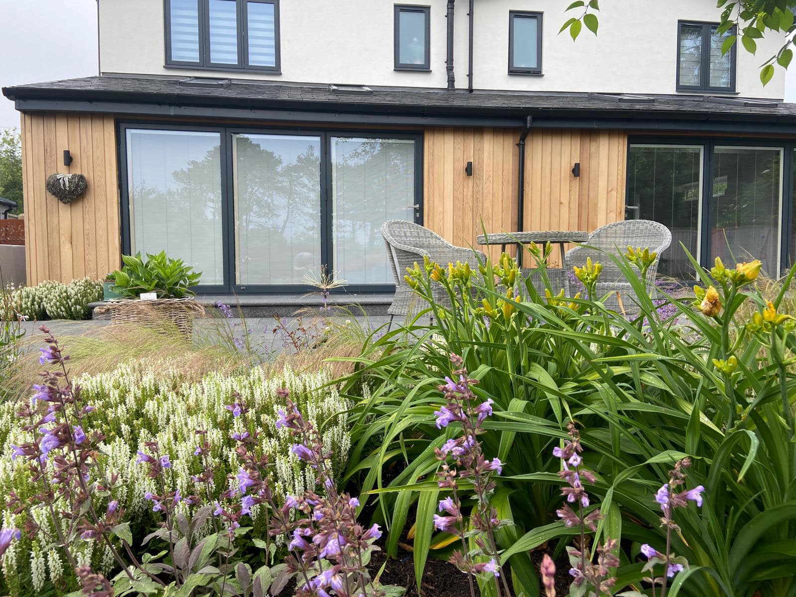 view of new living room extension across mature herbaceous planting