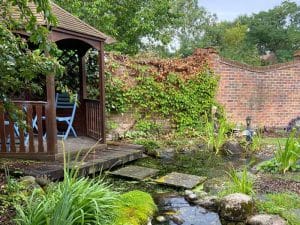 pretty wooden pergola sitting on a sturdy timber deck beside a wildlife pond