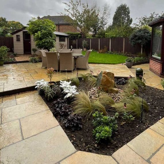 sandstone patio with water feature and plants in a central planting bed