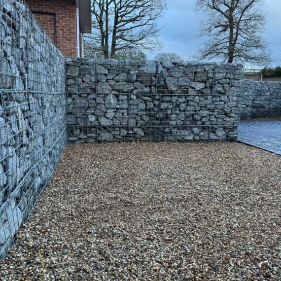 gabion baskets neatly filled with landscaping stone to create a rustic looking retaining wall
